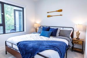 a bedroom with a bed with blue pillows and a window at Revy's Stellar Retreat in Revelstoke