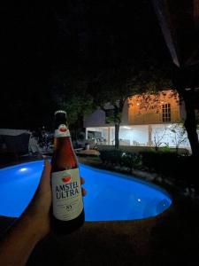 eine Person mit einer Flasche Bier neben einem Pool in der Unterkunft Beautiful Mountin Cabin/Pool/FirePit/Wifi/Parking in Monterrey