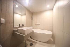 a white bathroom with a sink and a bath tub at Dongnae Hound Hotel Sajik Minam Station in Busan +31 photos