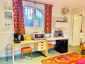 a kitchen with a desk with a microwave and chairs at Villa Vert in Beccar