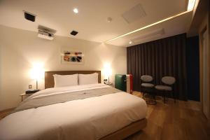 a bedroom with a large white bed and two chairs at Dongnae Hound Hotel Sajik Minam Station in Busan