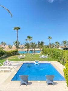 a swimming pool in a resort with palm trees at فيلا للايجار مارينا 5 الساحل الشمالي in El Alamein