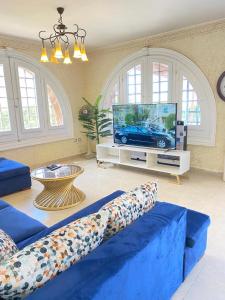a living room with a blue couch and a tv at فيلا للايجار مارينا 5 الساحل الشمالي in El Alamein