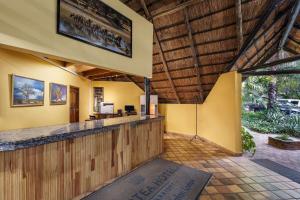 an outdoor bar in a resort with yellow walls and wooden ceilings at Protea Hotel by Marriott Lusaka Safari Lodge in Chisamba