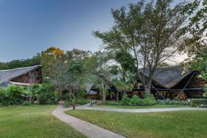 a house with a thatched roof and a grass yard at Protea Hotel by Marriott Lusaka Safari Lodge in Chisamba