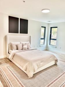 um grande quarto branco com uma grande cama com almofadas em Luxury Furnished Apartment in Heart of Quincy em Quincy