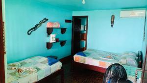 a bedroom with two beds and a blue wall at Hotel Cabinas Mar Y Cielo in Montezuma