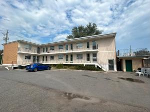 un coche azul estacionado frente a un edificio en Relax Motel en Thunder Bay