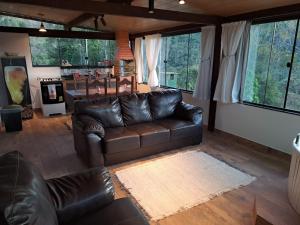 a living room with a leather couch and a table at Pousada e Spa Vrindávana in Teresópolis