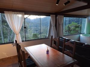 a dining room with a wooden table and large windows at Pousada e Spa Vrindávana in Teresópolis