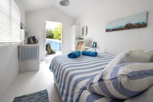 a bedroom with a bed with blue pillows on it at Boatsheds on the Bay, Waiheke Island in Ostend