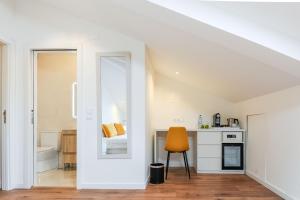 a white kitchen with a mirror and a chair at Boutique Room Montijo in Montijo