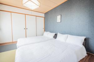 two beds in a room with white sheets at Ezo Fujiya Niseko House in Kutchan