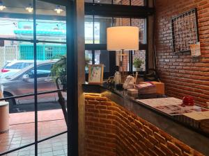 a restaurant with a brick wall and a window at MEEMAW'S House Hostel in Bangkok