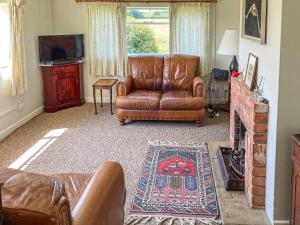 a living room with a leather couch and a television at Edgecoombe in Shaftesbury