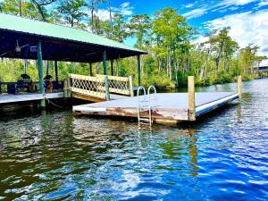 a dock with a bed on the water at Secluded cabin on the water with jet skis, kayaks, & hot tub! Pet friendly in Satsuma