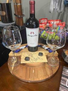 a bottle of wine on a wooden table with two glasses at Secluded cabin on the water with jet skis, kayaks, & hot tub! Pet friendly in Satsuma