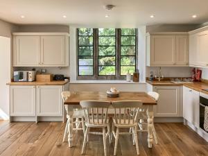 a kitchen with white cabinets and a wooden table and chairs at The Old School in Kettlewell