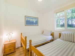a bedroom with two beds and a nightstand and two windows at Keepers Wood - W43109 in Bradworthy