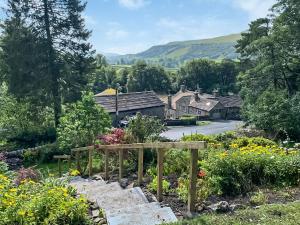 a garden with flowers and houses in the background at The Old School in Kettlewell