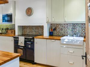 a kitchen with white cabinets and a black stove at Brookside Cottage in Copley
