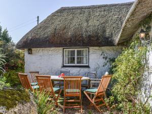 a table and chairs in front of a thatched house at No Place in Sennen