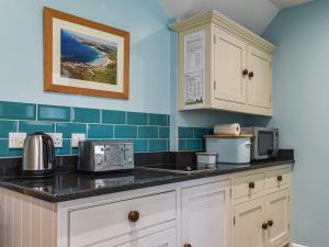 uma cozinha com armários brancos e azulejos azuis em No Place em Sennen