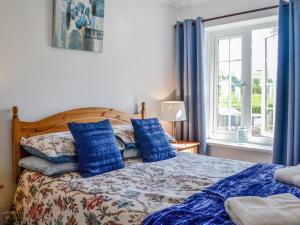 een slaapkamer met een bed met blauwe kussens en een raam bij Stoneybeck-uk45044 in Greenhead