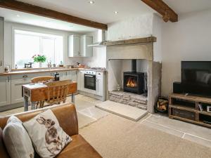 a kitchen with a living room with a fireplace at Little Badger Cottage in Kirkburton