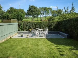 a patio with a table and chairs in a yard at Little Badger Cottage in Kirkburton