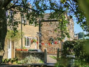 a brick house with a gate with a red ribbon at Little Badger Cottage in Kirkburton