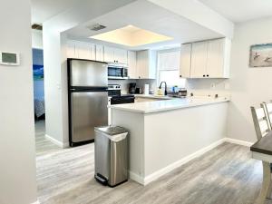 a kitchen with white cabinets and a stainless steel refrigerator at Sandy Beach Sunset West in Clearwater Beach