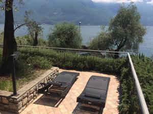 a bench sitting on top of a stone walkway next to a lake at Hotel Locanda Ruscello Garnì in Limone sul Garda
