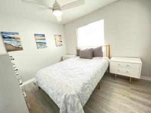 a white bedroom with a bed and a window at Beachside Getaway West in Clearwater Beach