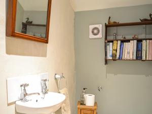 a bathroom with a sink and a mirror and a book shelf at North Corner in Carsethorn