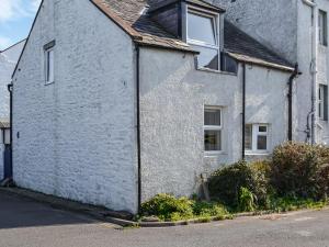 a white brick house with a window on a street at North Corner in Carsethorn