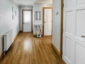um corredor com pisos em madeira, paredes brancas e portas brancas em Gramsdale House em Gramisdale