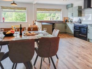 uma cozinha com uma mesa e cadeiras com copos de vinho em Beech House em Torcastle