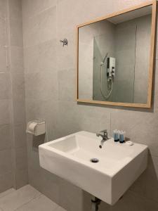 lavabo blanco en el baño con espejo en The Daily Hotel, en Kota Kinabalu