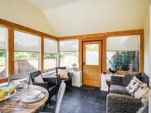 a living room with a table and chairs and windows at Orchard View in Minsterley