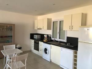 a kitchen with white appliances and a table and chairs at punta di buturetu in Propriano +6 photos