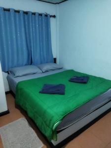 Schlafzimmer mit grünem Bett und blauen Vorhängen in der Unterkunft Andaman Peace Resort in Ranong
