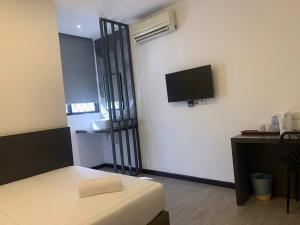 a room with a bed and a tv on a wall at The Daily Hotel in Kota Kinabalu