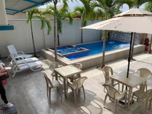 a table and chairs with an umbrella next to a swimming pool at Casa Halley #4 con vista al mar y piscina , 2 pisos - Villamil Playas , Data de Villamil in Playas