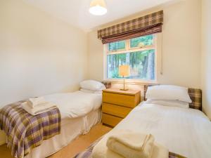 two twin beds in a room with a window at Burnside West Cottage- Uk39596 in Strathkinness