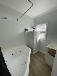 baño blanco con bañera y ventana en Giants Table and Cottages, en Maydena