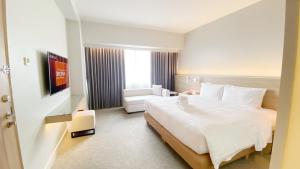a hotel room with a large white bed and a chair at Brittany Hotel BGC in Manila
