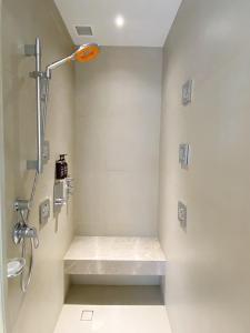 a shower stall with a bench in a bathroom at Brittany Hotel BGC in Manila