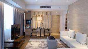 a living room with a white couch and a table at Brittany Hotel BGC in Manila