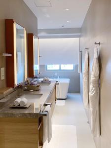 a bathroom with two sinks and a bath tub at Brittany Hotel BGC in Manila